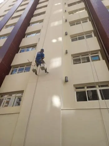 Profissional em acesso por cordas durante a obra de fachada